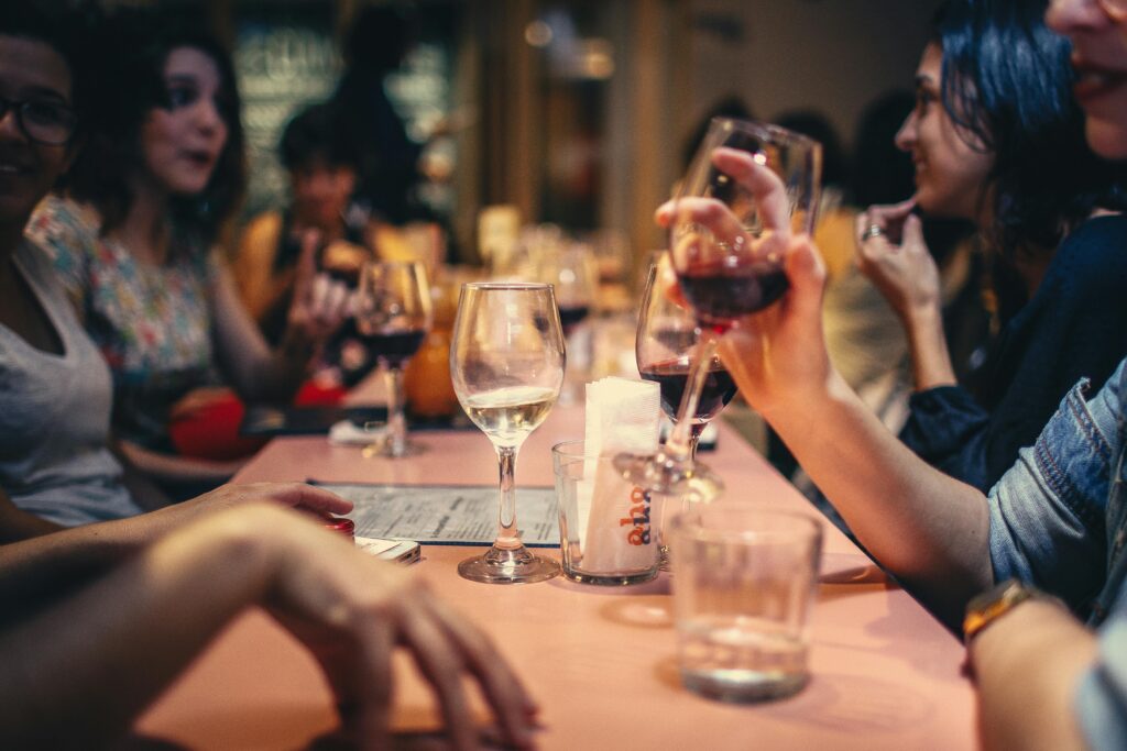 A lively scene of friends enjoying wine and conversation in a cozy bar setting.